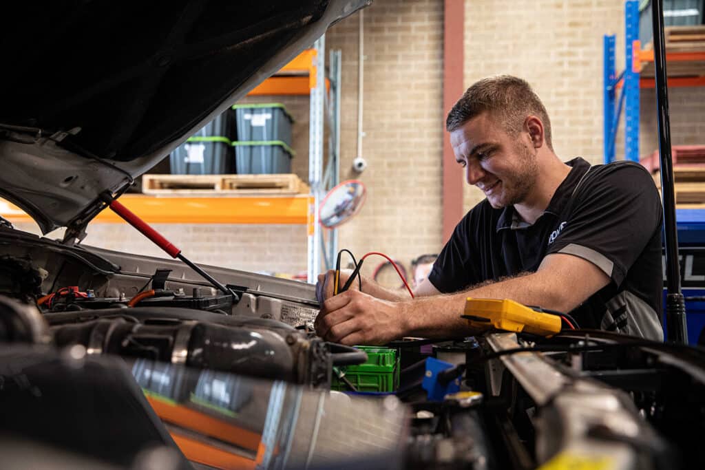 A happy auto electrician employee testing the auto electrics of a dual battery system