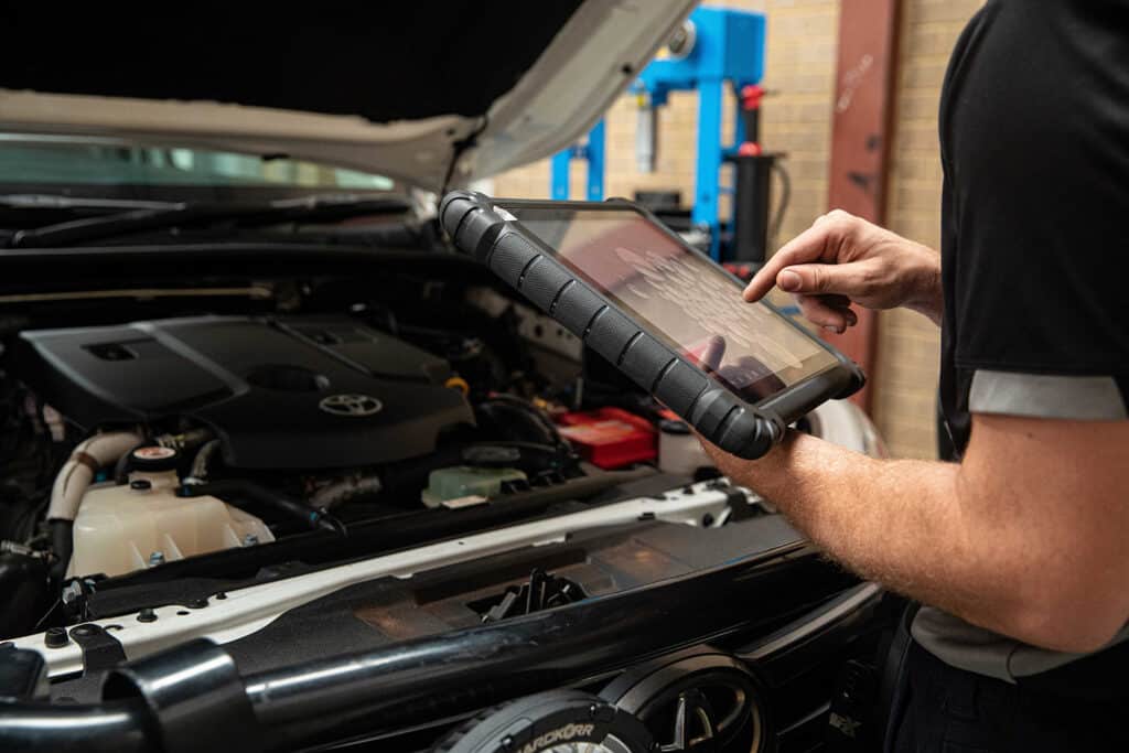 A voltaic employee using new technology to inspect a vehicle dual battery system