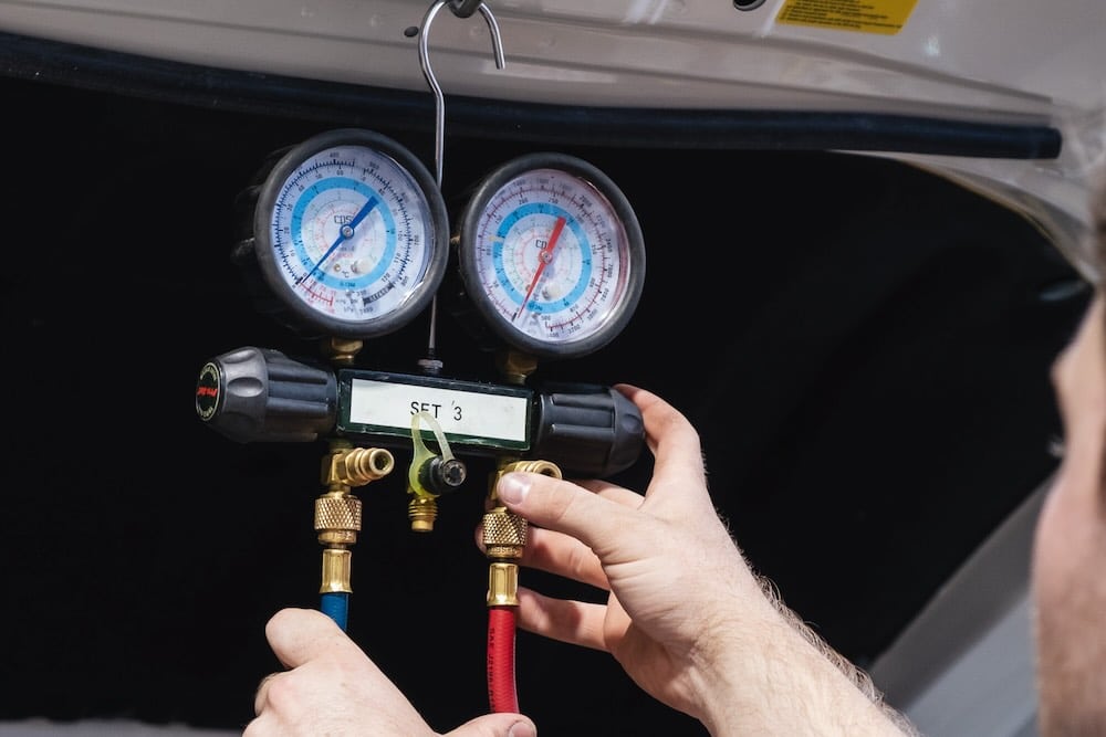 Auto electrician checking the types of car AC refrigerant